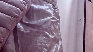 Confident 40-year-old woman tries on tight jeans in clothing store, showcasing her exaggerated curves.