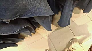 Confident 40-year-old woman tries on tight jeans in clothing store, showcasing her exaggerated curves.