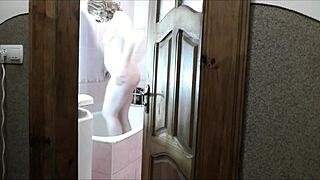 Does this naked sexy blonde in the bathroom notice her pervert roommate watching her masturbate and cum?